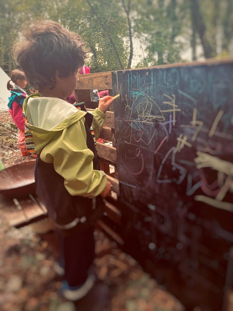 child drawing on a blackboard with chalk